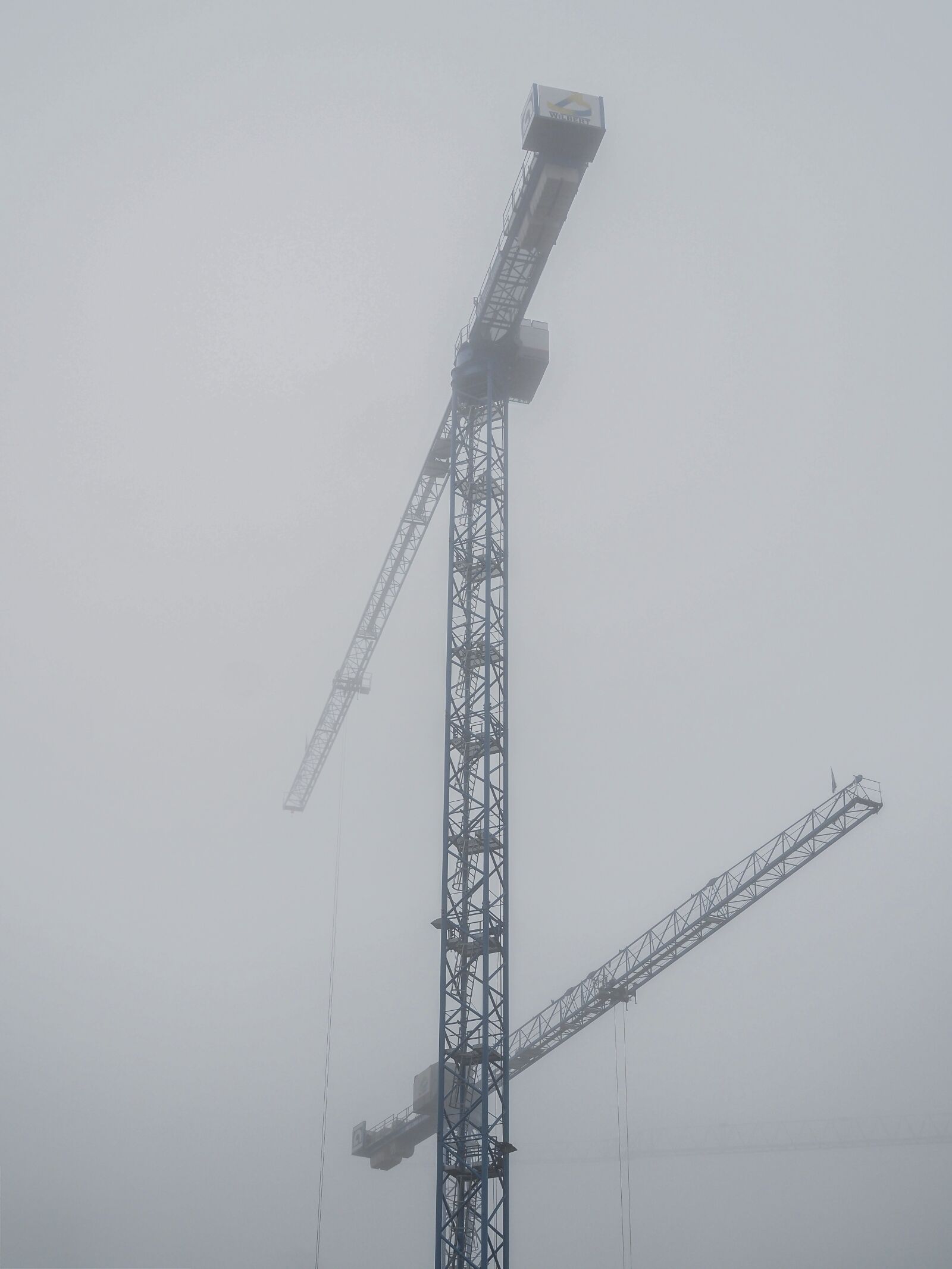 Olympus OM-D E-M10 + Olympus M.Zuiko Digital 25mm F1.8 sample photo. Construction cranes, site, fog photography