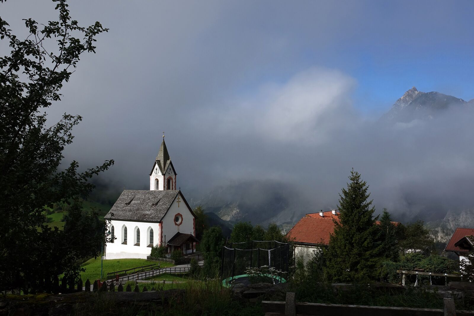 Sony Cyber-shot DSC-RX10 III sample photo. Church, houses, fog photography